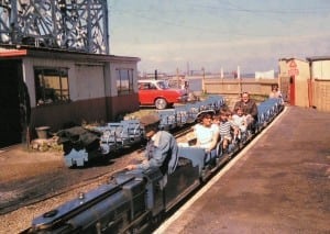 1970 approx: No, this is not Reg commuting to the office. He is on board the miniature railway which used to be at the end of Cleethorpes Promenade, with niece Sally  Riding, her brother Simon and others. The Dock Tower soars in the background, marking his place of business.